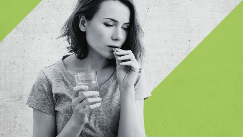 woman takes the pill, in her other hand she has a glass of water