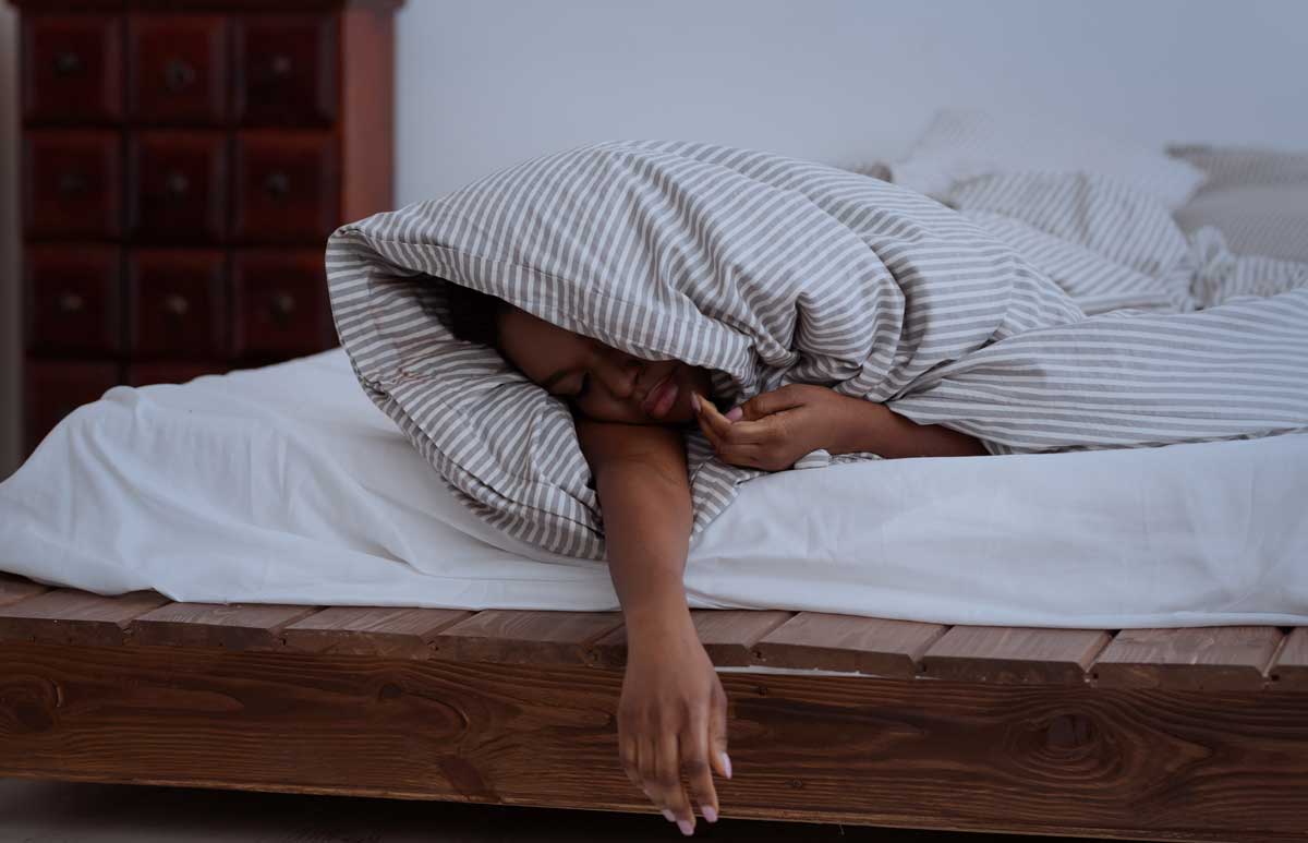 Sufficient sleep, deep sleep, sleep disorders, problems and insomnia at night. Sad tired woman in blanket sleeping on bed inside bedroom, dark, panorama, empty space